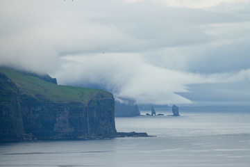 Fototapeta na wymiar AERIAL: Breathtaking view of the rugged coastline in Faroe Islands on cloudy day