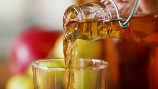 drinks and harvest concept - hand pouring apple juice from bottle to glass