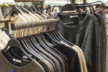 Fashionable men's and women's clothing on wooden hangers in a modern clothing store. 