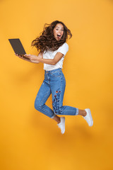 Full length portrait of a pretty girl with long dark hair jumping