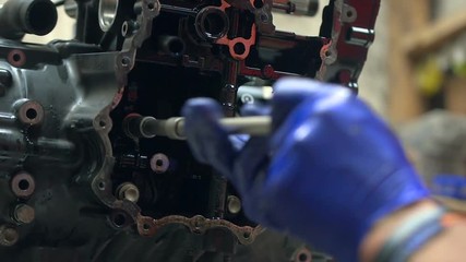 Mechanic try to disassembles motorbike engine using screwdriver. 