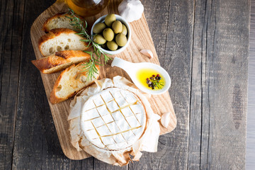 Baked camembert cheese. Fresh Brie cheese and a slice on a wooden board with nuts, honey, rosemary,...
