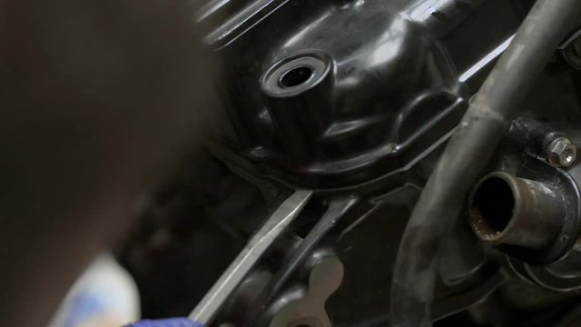Mechanic try to disassembles motorbike engine using screwdriver.