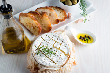 Baked camembert cheese. Fresh Brie cheese and a slice on a wooden board with nuts, honey, rosemary,...