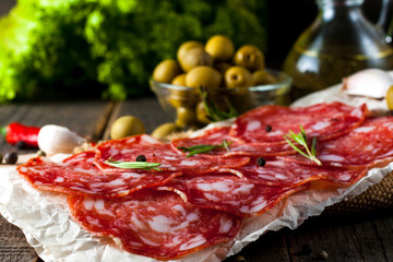 Chorizo sausage and salami, thin cut. spanish salami on the wood background with spices, paprika, pepper. Spicy food. Chili.