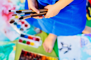 Close up of hands little girl in blue apron drawing still life with brush paints in summer park. Creative child painting on nature. Outdoors activity for children. Talented painter.