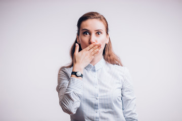 Surprised beautiful business woman on white background. Girl closes her mouth with her hand
