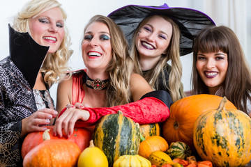 Four cheerful beautiful women toasting while celebrating Halloween together during costume party...