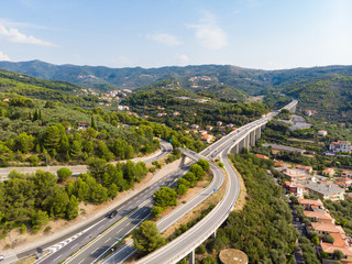 Aerial view of multiple lane highway crossing villages and forest hills (Autostrada dei Fiori - A10) Liguria Italy