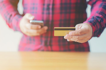 Man's hands holding a credit card and using smart phone for online shopping online payment