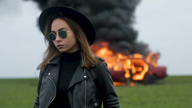 A man in the background of a burning car, a fashionable girl in a hat, a burning car, a car version