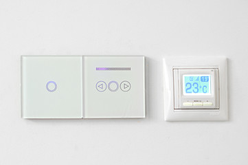 smart home system, switches and floor heating on white wall. Digital thermostat temperature controller