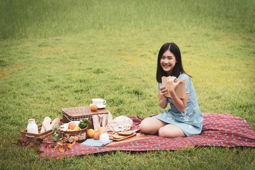 A girl going picnic in a park and reading a book