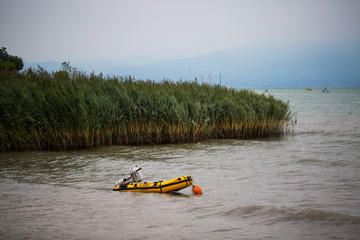 Dinghy with engine in the lake, yellow dinghy, reed