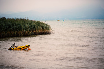 Dinghy with engine in the lake, yellow dinghy, reed
