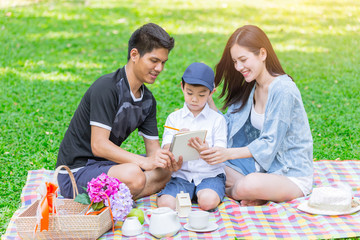 Asian teen family teaching son homework while picnic at outdoor park