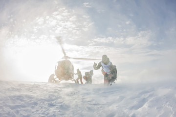 landing from the helicopter skiers freeriders in the snowy mountains in winter