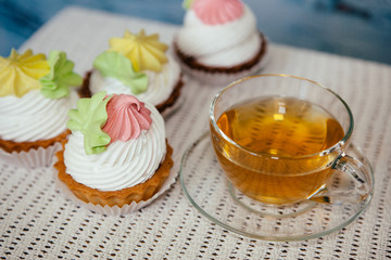 Cup of tea with pink and yellow cupcakes on table, sweet food with hot drink