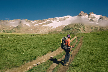 Fototapeta na wymiar woman with a backpack, hiking with trekking poles in mountain . Hiking around Mont Blanc
