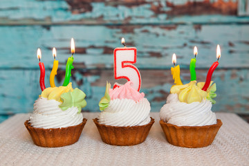 Happy fifth birthday cake and number five candle on blue background, anniversary celebration
