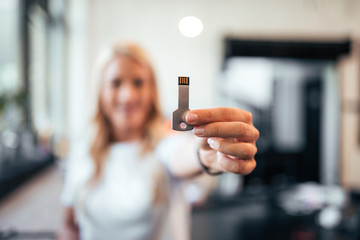 Woman holding a usb key. Focus on a foreground, on the usb. - obrazy, fototapety, plakaty