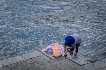 woman cleaning clothes at yangshuo river