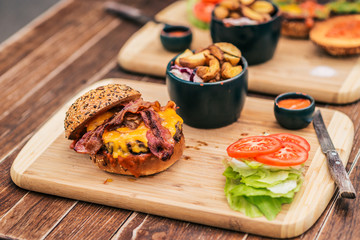 Tasty burger with bacon an a wooden plate.