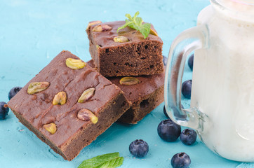 Pieces of brownie on blue background with blueberries.