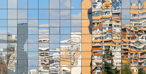 Residential buildings are reflected in the mirror windows of another building
