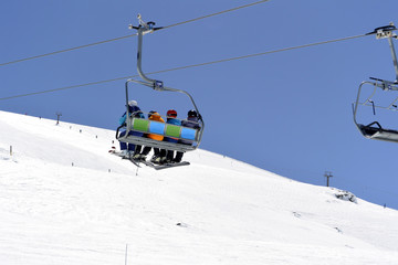 Fototapeta na wymiar White snow-capped mountain slopes with skiers and a ski lift with skiers 