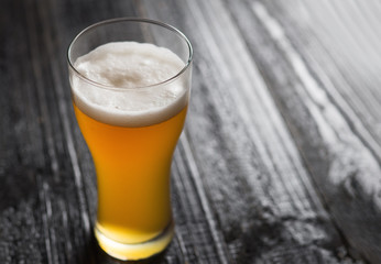 Light unfiltered wheat beer in a glass on a black table with copy space