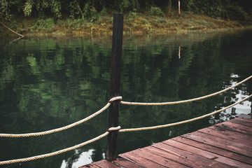 Fototapeta premium Rope fence on the old wooden walk way near the lake.