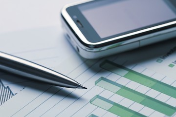 Mobile Phone And Pen On Financial Graphs Close-up
