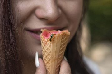 insect is sitting on the ice cream that the girl is eating, an bite is possible.