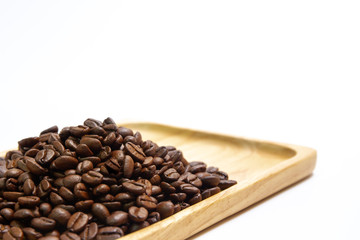 Medium roasted organic coffee beans on wooden plate close up.