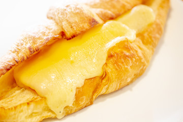 Baked ham - cheese croissant in a dish on wooden table close up.
