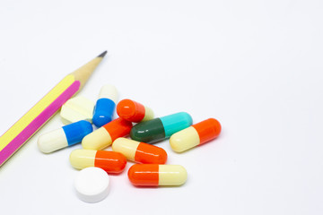Pills and capsules on white background with a pencil, concept of medical and health care.