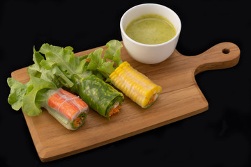 Fresh vegetable noodle spring roll with sauce on wooden tray, Salad roll, On a black background. Diet or cook concept.