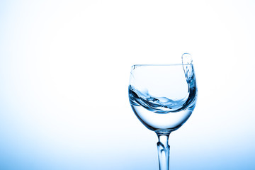 Water splashing in the luxury wine glass close up.  Concept of good healthy and refreshment.  Copy space on left side on the image.