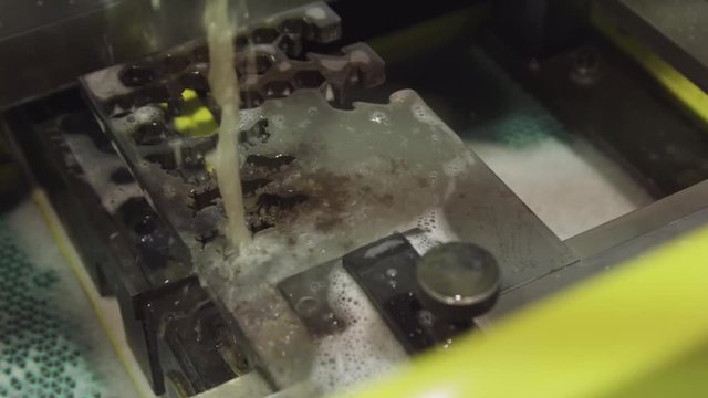 Close-up of the wire - EDM CNC machine while cutting the sample work pieces in light blue tone and lighting effect. Close-up of the wire - EDM CNC machine while cutting the sample work pieces in light