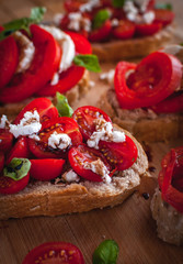 Close-up of bruschetta with cheese, tomatoes, fresh basil and balsamic vinegar on cutting board
