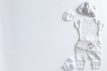 Set of unisex clothing and accessories for a baby in neutral colors, top view and flat lay on white background