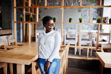 African muslim girl in black hijab and sunglasses posed at modern cafe .