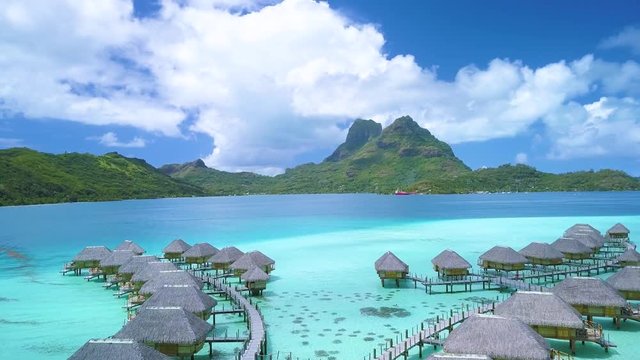 Aerial footage from a drone of luxury overwater villas with palm trees, blue lagoon, white sandy beach and Otemanu mountain at Bora Bora island, Tahiti, French Polynesia (Bora Bora Aerial)
