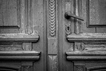 Fragment of the old door and door handle. Background. Black and white.