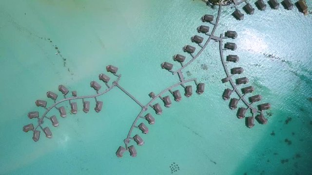 Aerial footage from a drone of luxury overwater villas with palm trees, blue lagoon, white sandy beach and Otemanu mountain at Bora Bora island, Tahiti, French Polynesia (Bora Bora Aerial)
