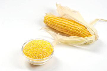 Corn meal in a glass bowl. White background. Close-up. Macro photography.
