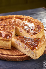 Appetizing cheese cake with sausage, ham. Snack unsweetened cake with crispy cheese crust. An unusual variant of pizza is 