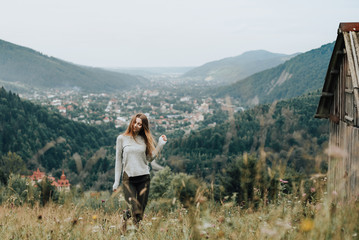 Fototapeta premium Happy young girl is having fun time on the background of the mountains outdoor