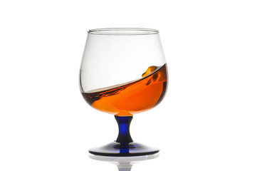 Glass with splashes cognac isolated on white background